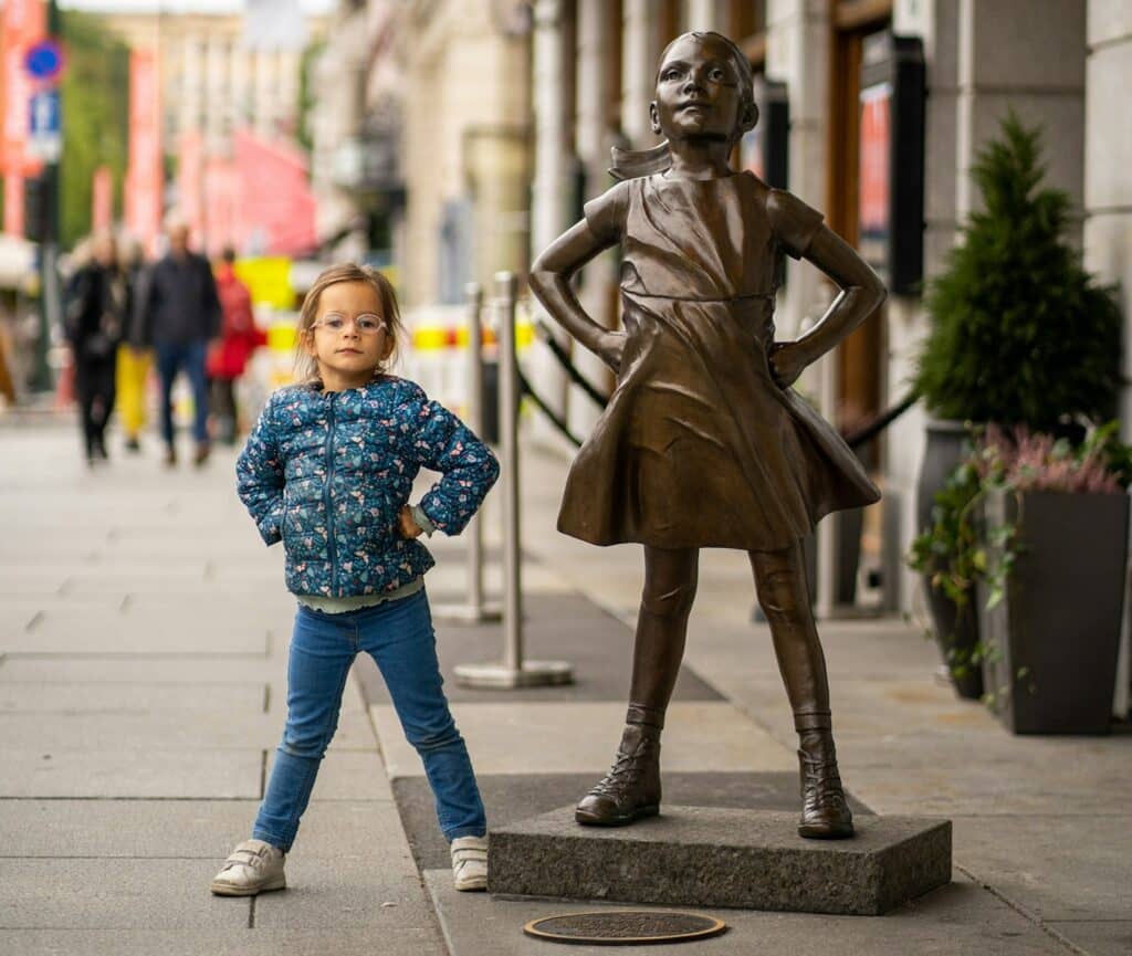 ילדה עומדת ליד פסל רחוב באוסלו